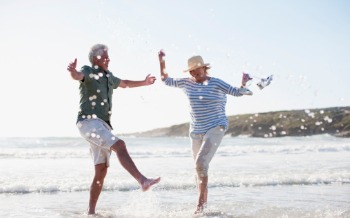 Older couple on beach splashing 